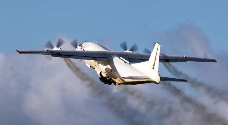 Old cargo airplane taking off with turboprop engine smoke emission.