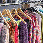 A rack of colourful and highly patterned second hand vintage clothes for sale on a London street.